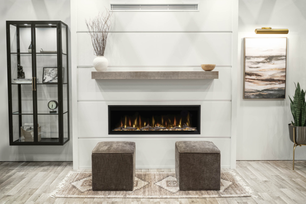 Contemporary living room with a built-in fireplace, a floating mantle, and two square brown ottomans on a patterned rug.